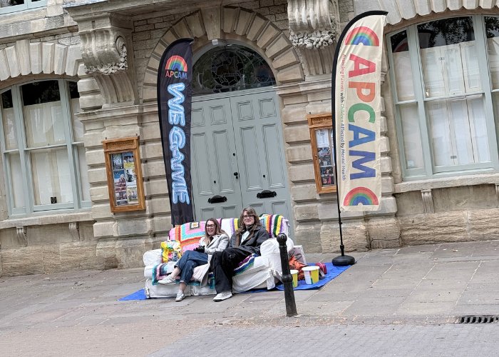 Two of the APCAM team on our rainbow sofa outside Witney Corn Exchange